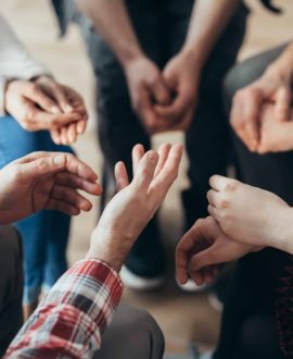 Close-up of hands of people sitting in a circle during a therapy group meeting